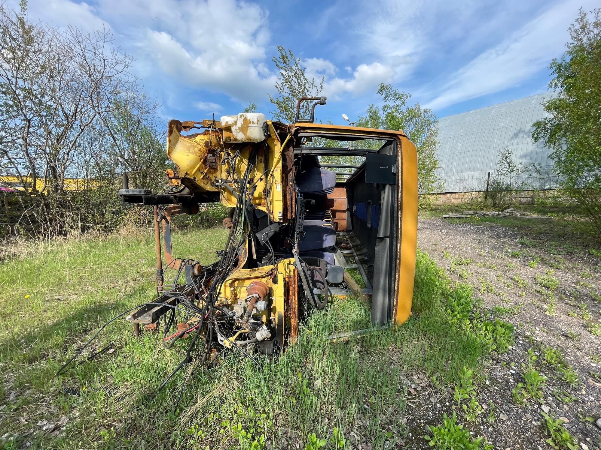 Apgadintas geltonos spalvos nedidelės talpos autobusas, pavirtęs ant šono